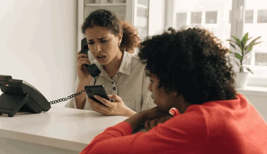 Recepcionista com telefone e celular ao mesmo tempo